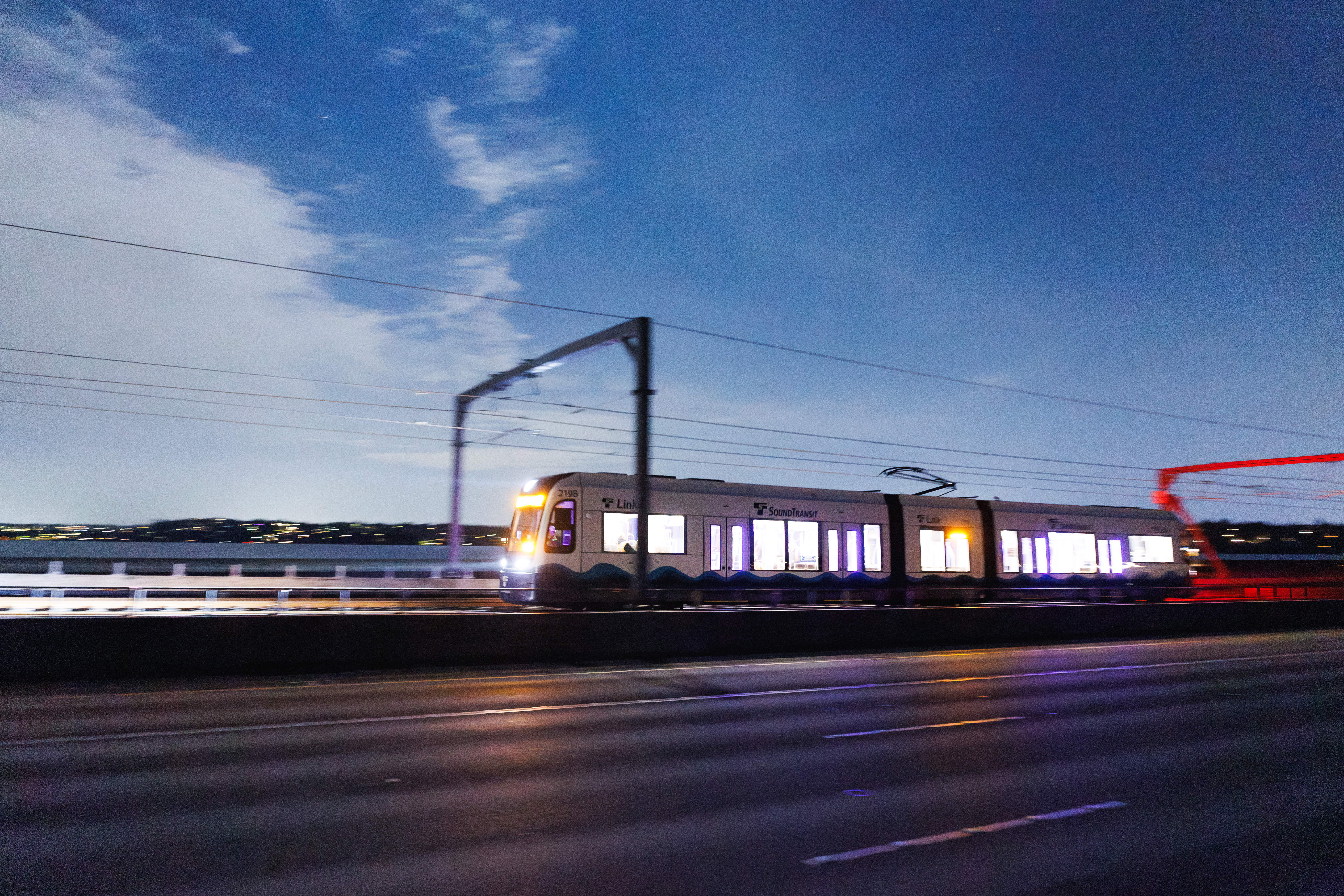 A light rail vehicle (LRV) crosses the floating bridge under its own power during the first night of Crosslake livewire testing on September 8, 2025